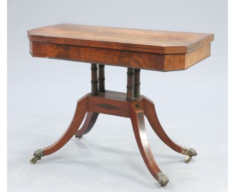 A REGENCY MAHOGANY FOLDOVER CARD TABLE, the flame mahogany top with canted corners, raised on two pairs of ringed columns iss