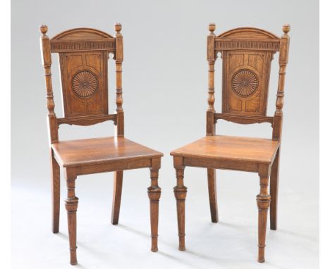 A PAIR OF AESTHETIC MOVEMENT OAK HALL CHAIRS, CIRCA 1880, each with arched crest above a carved back panel and boarded seat.&