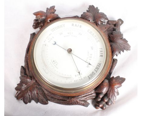 A barometer with white enamel dial and fruit carved oak case