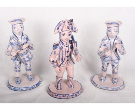 A set of three continental earthenware figures of Napoleonic soldiers with rifle, drum and pipe, decorated in blue on crackle