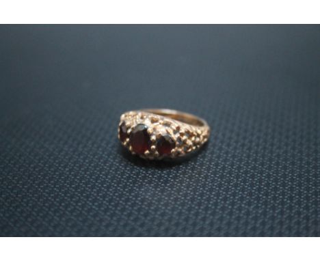 A 9CT GOLD THREE STONE GARNET RING IN RAISED PIERCED GALLERY SETTING, approx weight 4.3g, ring size K