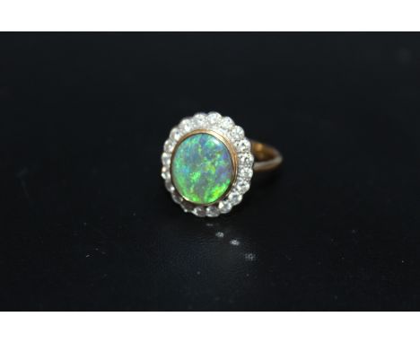 A HALLMARKED 18 CARAT GOLD OPAL AND DIAMOND RING, the central oval opal being of an estimated 2.33 carats surrounded by 20 br