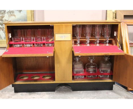 A VINTAGE TEAK AUSTIN FITTED TRAVELLING DRINKS CABINET, having four compartments with assorted champagne glasses, tumblers an