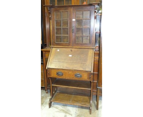 An Edwardian low oak bureau bookcase, the top fitted with a pair of glazed doors above a fall front, single drawer, shelf and