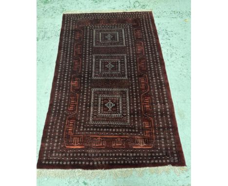 A red ground wool rug with geometric border in an Aztec style pattern 200x124