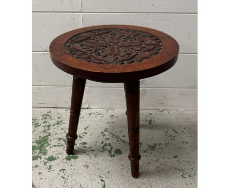A vintage carved tripod stool on turned legs 