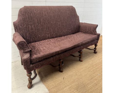 A French style high back sofa on ornate carved legs and upholstered in a purple fabric featuring columns, sea horses and bird
