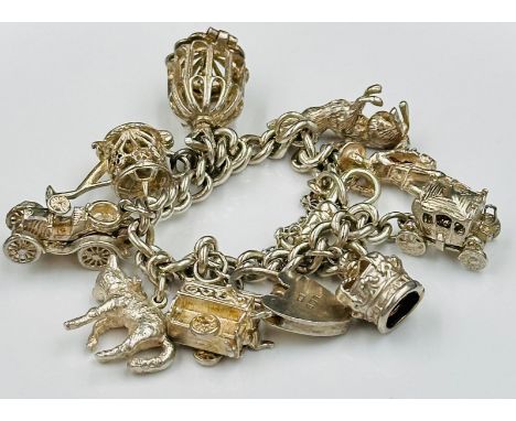 A silver charm bracelet with a variety of charms to include: crown, royal coach, cat, car etc. Approximate weight 54g