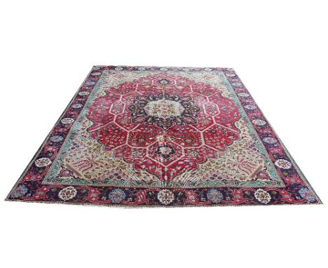 A Tabriz wool carpet, worked with a central medallion, geometric and foliate motifs against a red ground, 328cm x 277cm