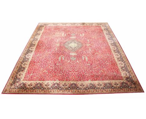 A large red ground carpet, decorated all-over with a stylised tree of life design, floral sprays and central medallion, withi