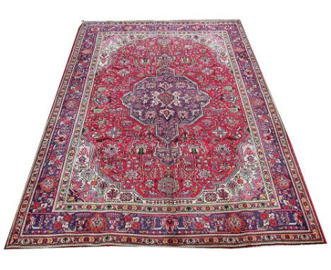 A Caucasian wool carpet worked with a central medallion and all over foliate design against a red ground, 298cm x 204cm