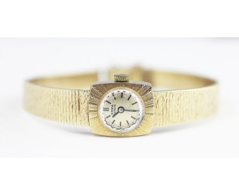 A ladies 'Emka Geneve' 18k gold wristwatch, the cushion shaped face enclosing champagne coloured circular dial with batons, a