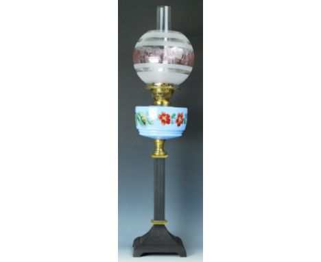 An oil lamp with a blue glass opaque reservoir painted with floral vines, 76cm high