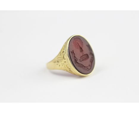 An intaglio set signet ring, the carnelian carved oval seal depicting peacock crest and motto, all set in 18ct yellow gold, w