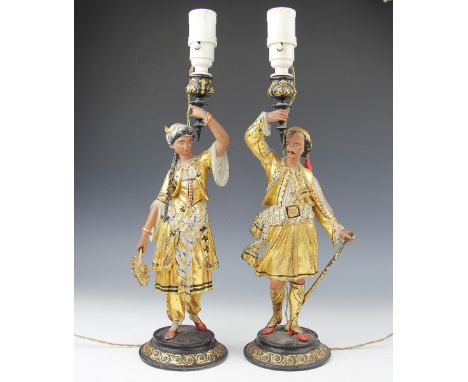 A pair of figural lamp bases, each gilt painted and modelled in typical eastern costume, 37cm high (excluding fittings) Light