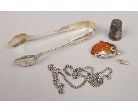 A group of silver items including a pair of sugar tongues, along with an amber pendant and chain (for repair) and a thimble.