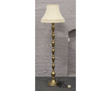An ornate brass standard lamp with cream shade.