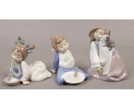 Three Nao porcelain figures including a young girl with rabbit and two children wearing bibs.