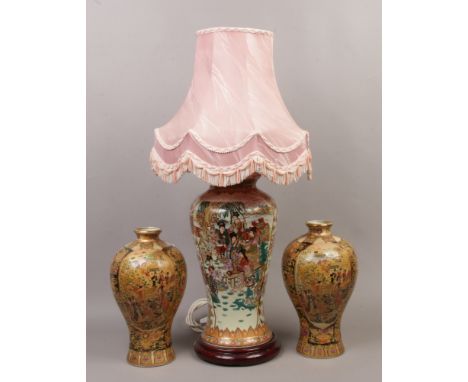 A Satsuma style high shouldered ceramic table lamp with pink fabric shade, along with a pair of similar vases.