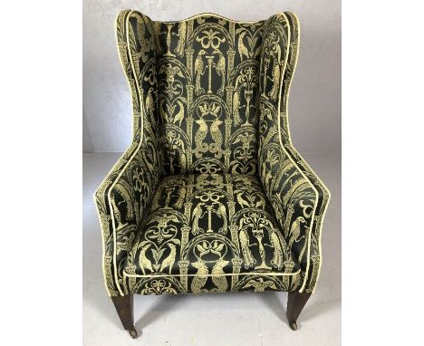 Elegant wing-backed upholstered arm chair on square tapering legs and ceramic castors