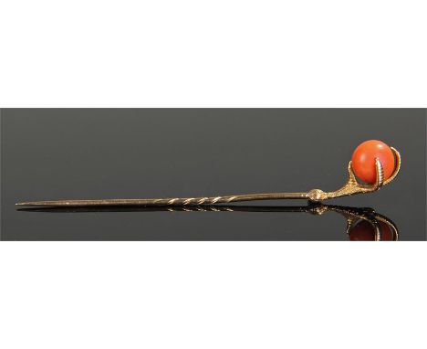 Yellow metal and coral stick pin, formed as an eagle claw holding a coral sphere, 8.5cm high