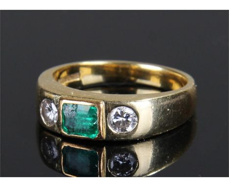 18 carat gold emerald and diamond set ring, the central emerald flanked by a pair of diamonds, ring size M