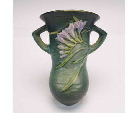 Crafted by Roseville Pottery, this wall pocket from the Freesia line displays the hallmark high-relief floral design with sof