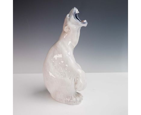 This expressive porcelain figurine by Royal Copenhagen depicts a roaring polar bear seated on its haunches, mouth open with l