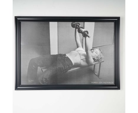 Striking black and white framed poster of Marilyn Monroe in a rare and playful pose, captured mid-rep while lifting dumbbells