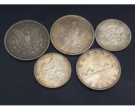 A 1885 Morgan Dollar, 1924 peace dollar, two 1964 half dollar coins and a 1953 Canadian dollar coin.