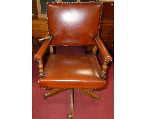 A contemporary joined oak tan leather upholstered and further brass studded swivel desk elbow chair, in the 17th century tast