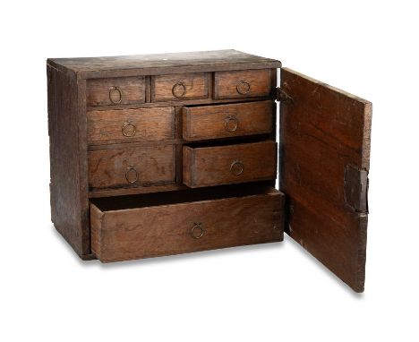 AN OAK SPICE CUPBOARD, LATE 17TH/ EARLY 18TH CENTURY the panel door enclosing eight drawers of various sizes, brass loop hand