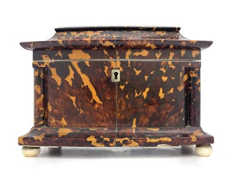 A Regency tortoiseshell tea caddy, circa 1820, of bow-fronted sarcophagus form with silver wire inlay, ivory bun feet, fitted