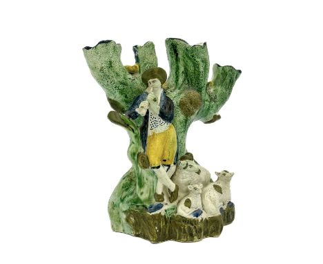 A Staffordshire four branch Prattware tulip vase, circa 1790, modelled as a piping shepherd with flock, beside a tree of nest