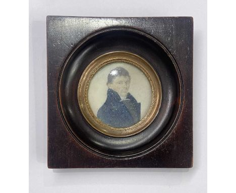 An early 19th century portrait miniature painted to depict a man in a high-collared blue coat, on ivory, 4.8 by 4.8cm, framed