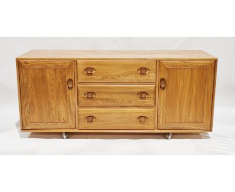 Ercol pale blonde elm windsor sideboard comprising a central bank of three drawers flanked by cupboards, raised on castors, 1