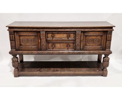 Reproduction oak dresser base in the Tudor manner by Titchmarsh and Goodwin,&nbsp;with carved foliate motifs and decoration t