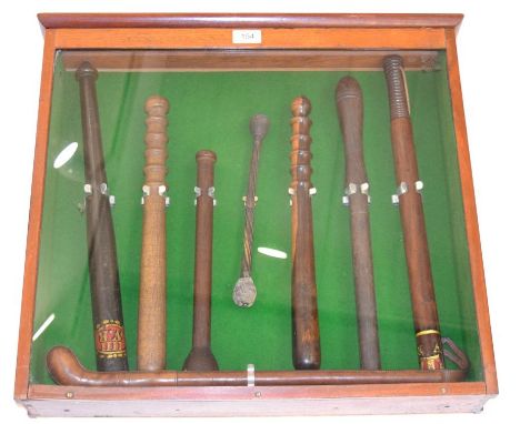 A Mahogany Glazed Display of Truncheons, comprising a William IV ebonised example, painted in gilt and red with Royal cypher;