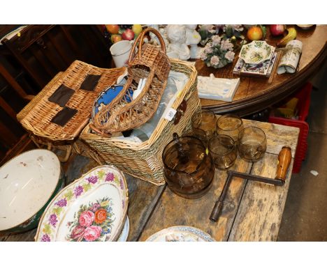 A wicker picnic hamper lacking contents; a wicker picnic hamper and contents; a wicker wine bottle holder; and a smoked glass