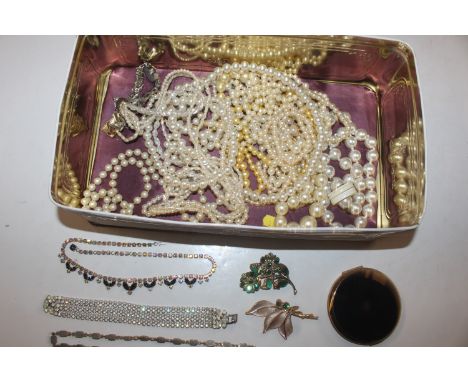 A tin containing simulated pearl necklaces, other jewellery and a compact 