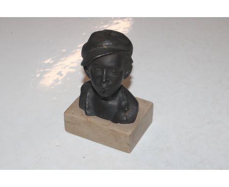 A bronze bust in the form of a young boy wearing a cap and smoking, signed to the reverse possibly&nbsp;De Martino