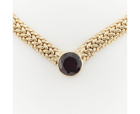 Zelman &amp; Friedman, United States. 14k yellow gold domed woven link V-shaped necklace set with a central round cut garnet.