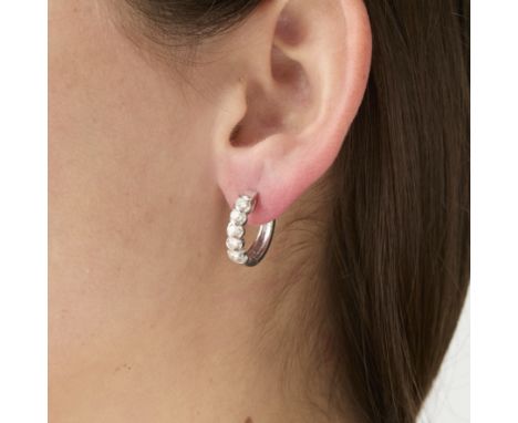 Pair of 14k white gold and diamond hinged hoop earrings. Each earring set with five round full cut diamonds, approximately 1 