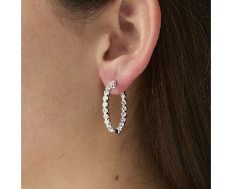 Pair of 18k white gold inside-out diamond hoop earrings. One earring set with 19 brilliant cut diamonds. The other set with 1