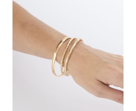 Group of three 14k yellow gold bangles including:14k yellow gold bangle bracelet, of simple design. Marked along the interior