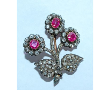 An early 20th century diamond and ruby brooch in the form of a flower spray. The flowers being set with oval and round cut ru