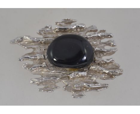 A large vintage brutalist textured white metal brooch with central black glass stone with roller clasp. Measures 6cms.