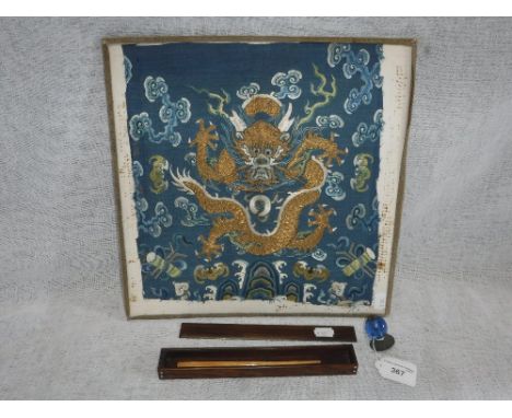 AN ORIENTAL EMBROIDERED PANEL depicting a dragon, a hardwood box containing two bone hair pins and a blue glass and brass Man