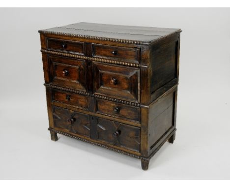 A late 17th century joined oak chest of four long drawers the three plank top with half bobbin turned moulded edge, the four 