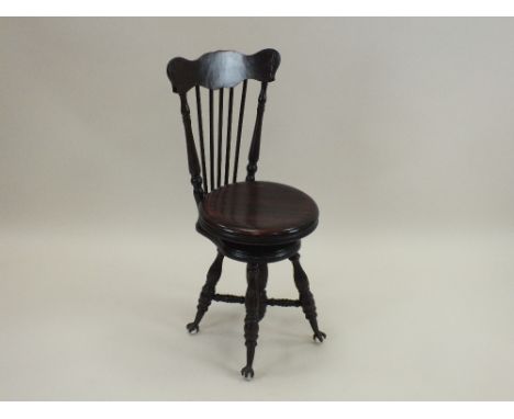 A Victorian mahogany music chair, possibly American, with stick back and circular swivel adjustable seat and raised on out sp